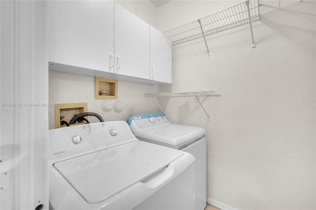 laundry room featuring washer and clothes dryer and cabinets