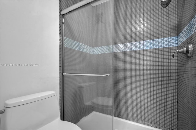 bathroom with a shower with shower door and toilet