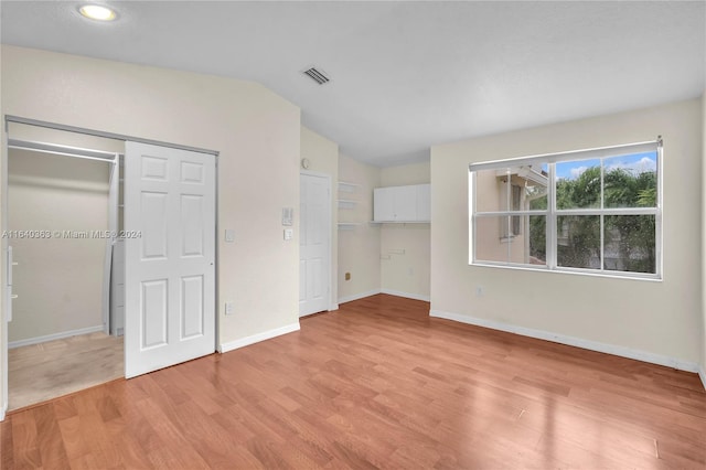 unfurnished bedroom featuring a closet, lofted ceiling, and light hardwood / wood-style floors