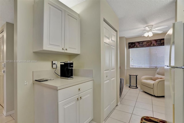 kitchen featuring light tile patterned floors, a textured ceiling, white cabinets, light countertops, and freestanding refrigerator