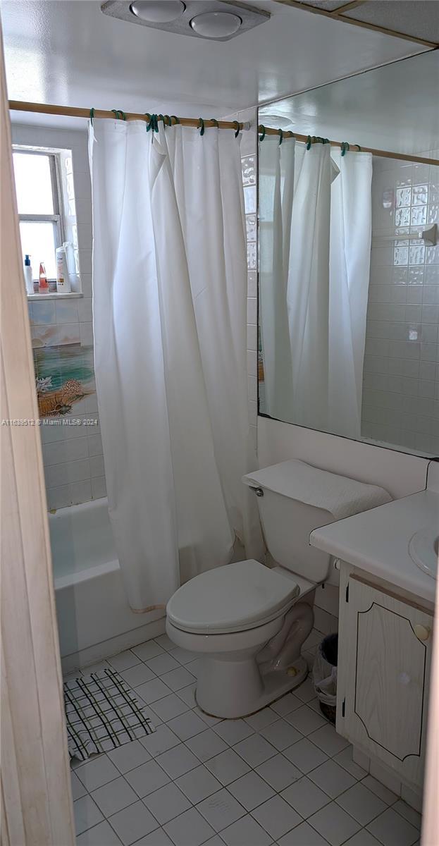 full bathroom featuring vanity, toilet, tile patterned floors, and shower / bath combo with shower curtain