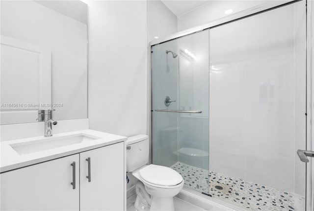 bathroom with a shower with shower door, vanity, and toilet