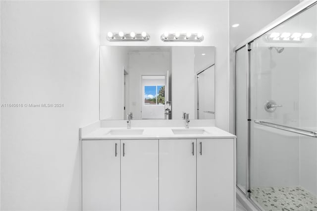 bathroom with double sink vanity and a shower with door