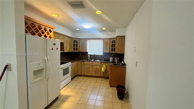 kitchen with light tile patterned flooring, sink, decorative backsplash, and white appliances