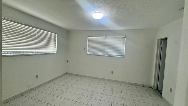 unfurnished room featuring a textured ceiling and light tile patterned floors