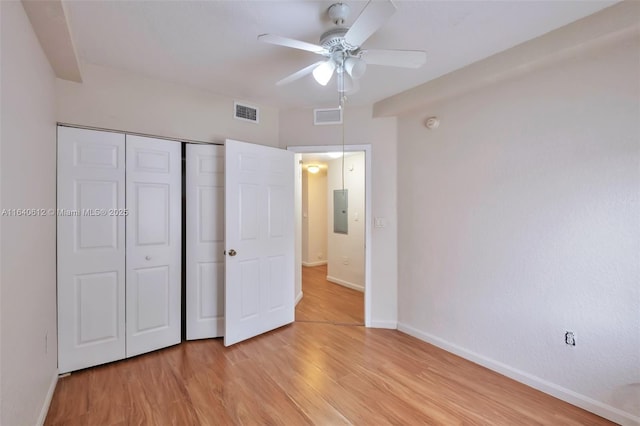 unfurnished bedroom featuring electric panel, a closet, light hardwood / wood-style flooring, and ceiling fan