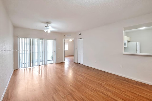 spare room with ceiling fan and light wood-type flooring