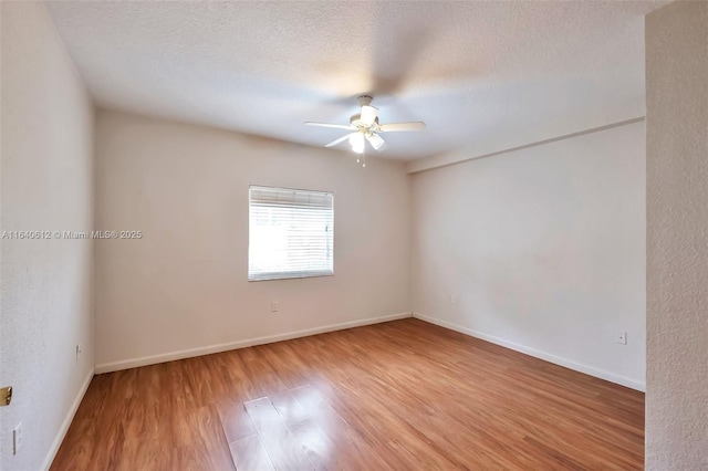 empty room with ceiling fan, wood-type flooring, and a textured ceiling