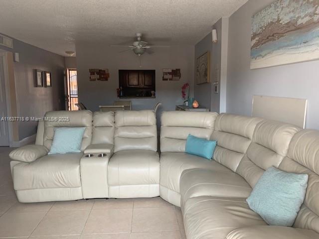 tiled living room with ceiling fan and a textured ceiling