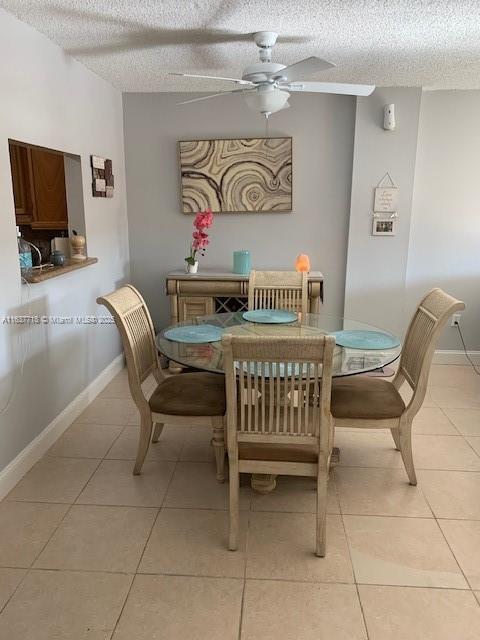 dining space with ceiling fan, a textured ceiling, and light tile patterned floors