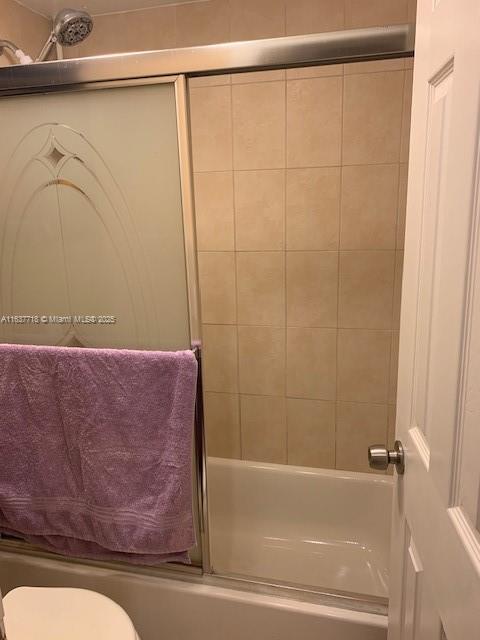 bathroom with shower / bath combination with glass door and toilet