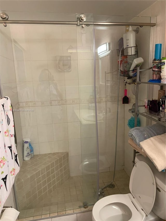 bathroom featuring a shower with door and toilet