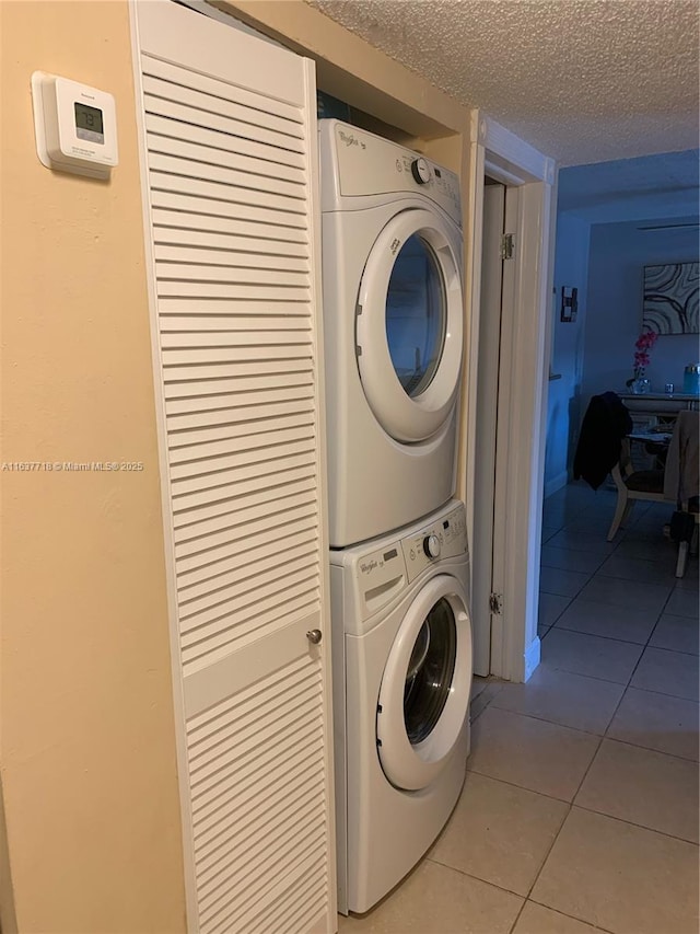 washroom with light tile patterned flooring, stacked washer and clothes dryer, and a textured ceiling