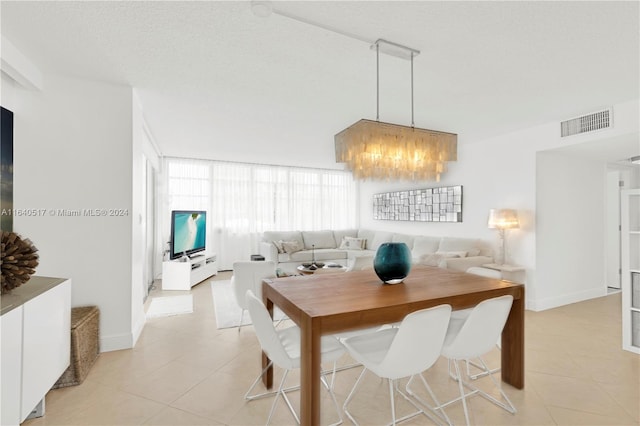 dining area with a textured ceiling, light tile patterned floors, and an inviting chandelier