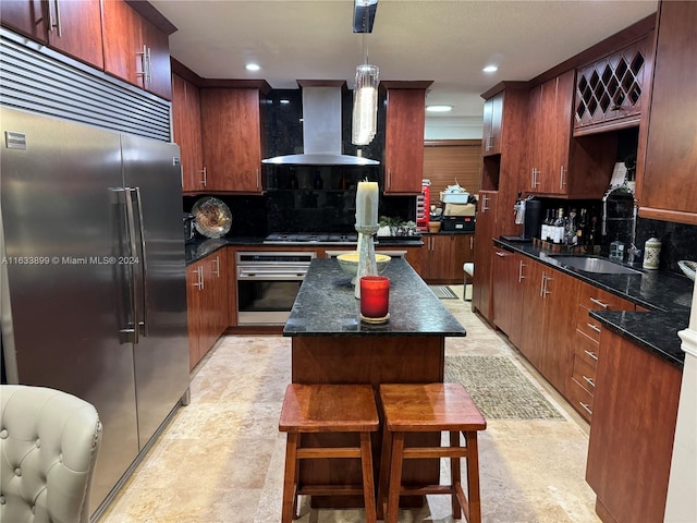 kitchen featuring appliances with stainless steel finishes, wall chimney exhaust hood, a center island, decorative light fixtures, and tasteful backsplash