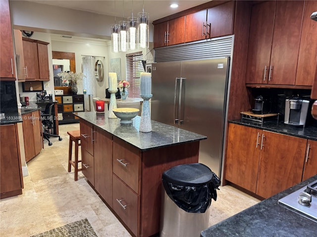 kitchen featuring built in fridge, a kitchen island, a breakfast bar, backsplash, and hanging light fixtures