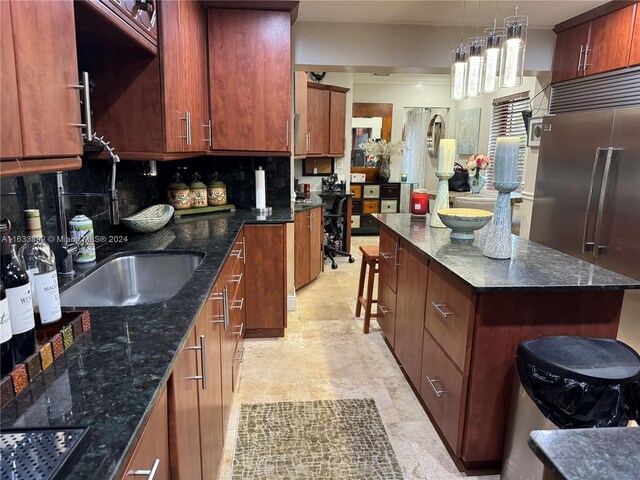 kitchen featuring dark stone countertops, light tile patterned floors, hanging light fixtures, a kitchen island, and backsplash