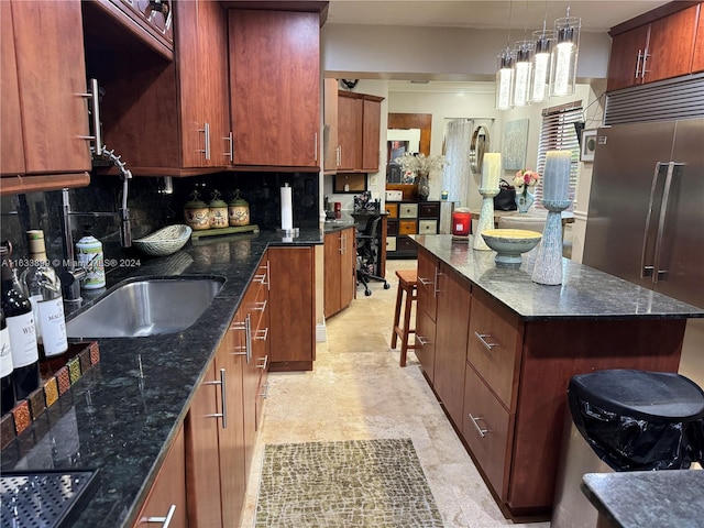 kitchen with hanging light fixtures, a center island, tasteful backsplash, a kitchen bar, and built in fridge