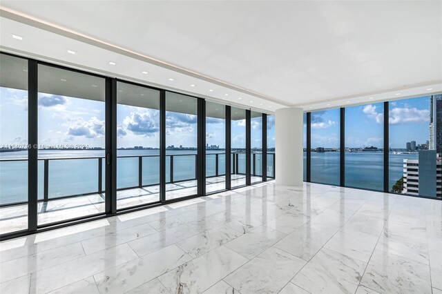 tiled empty room with expansive windows and a water view