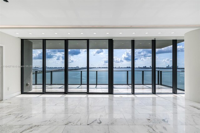 tiled spare room with floor to ceiling windows and a water view