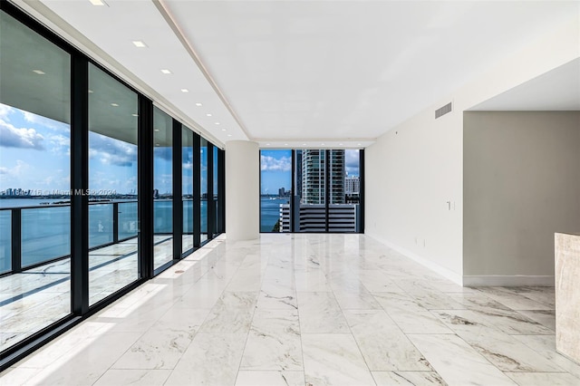 tiled spare room with a wall of windows, a wealth of natural light, and a water view