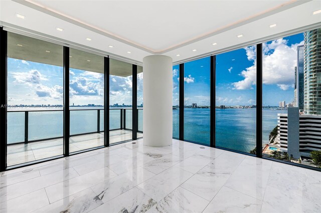 tiled spare room with a water view and a wall of windows