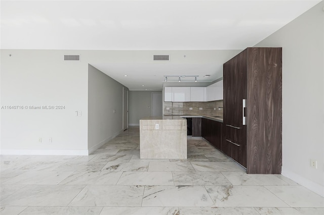 kitchen with white cabinets, tasteful backsplash, a center island, and light tile patterned floors