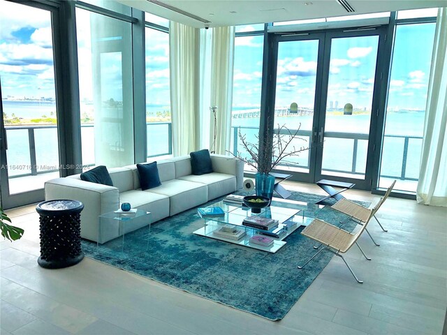 interior space featuring floor to ceiling windows, a water view, and hardwood / wood-style flooring