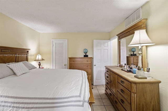 tiled bedroom featuring a textured ceiling and a closet