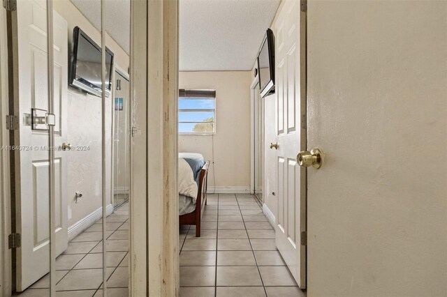 hall with a textured ceiling and light tile patterned floors