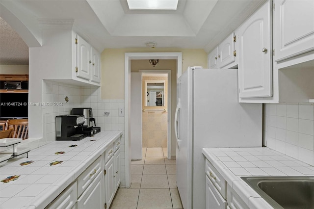 kitchen with backsplash, tile countertops, white cabinetry, and light tile patterned floors