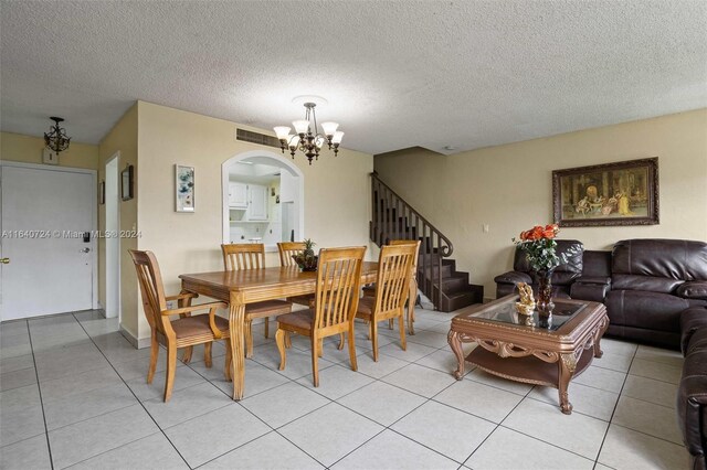 dining area with light tile patterned floors, a notable chandelier, and a textured ceiling