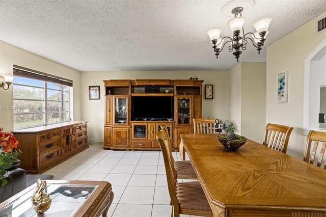 dining room featuring light tile patterned flooring, an inviting chandelier, and a textured ceiling