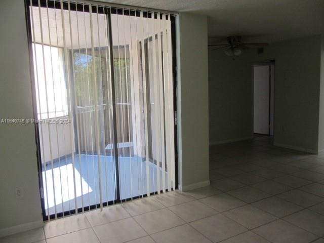 empty room with ceiling fan and tile patterned flooring