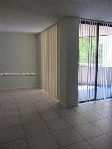 tiled empty room featuring a textured ceiling