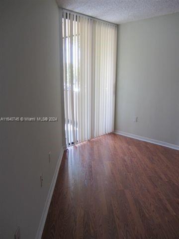 empty room featuring a healthy amount of sunlight, dark hardwood / wood-style flooring, and a textured ceiling