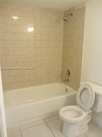 bathroom with tile patterned floors, toilet, and tiled shower / bath