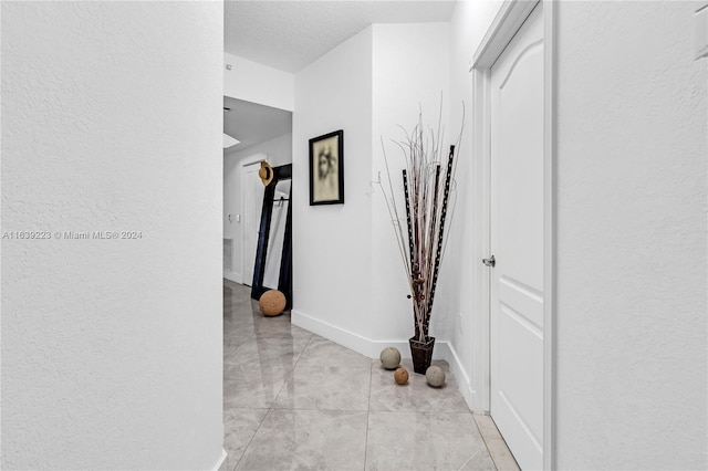 hall with baseboards and a textured wall