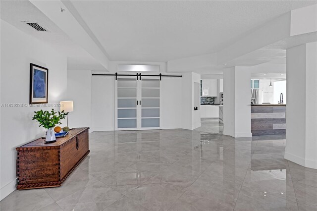 interior space with light tile patterned floors and a barn door