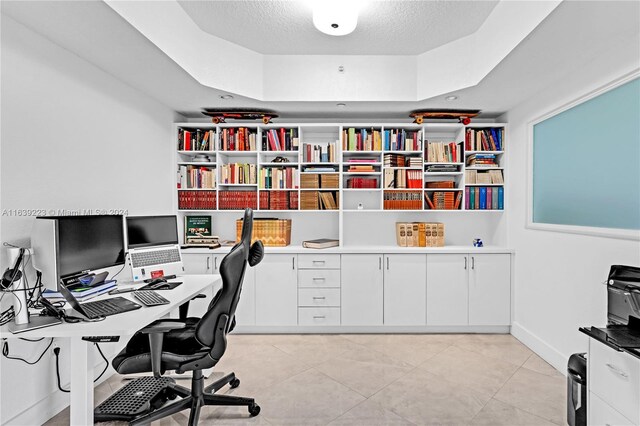 office space with light tile patterned floors, a raised ceiling, and a textured ceiling