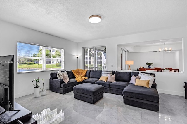 living room featuring baseboards, a textured ceiling, and an inviting chandelier