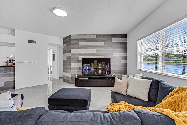 living room with tile walls, a textured ceiling, and light tile patterned floors