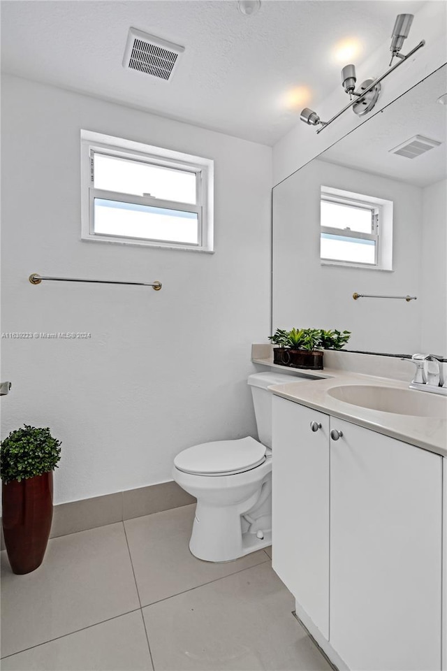 half bath with toilet, tile patterned flooring, vanity, and visible vents