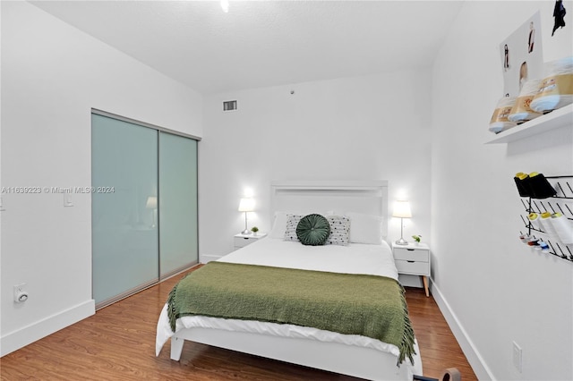 bedroom featuring baseboards, a closet, visible vents, and wood finished floors