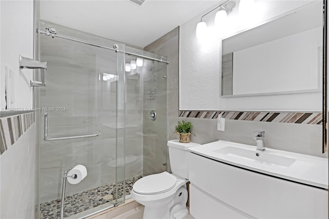 bathroom featuring toilet, a shower stall, and vanity