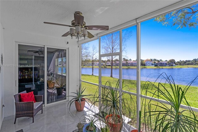 sunroom / solarium with ceiling fan and a water view