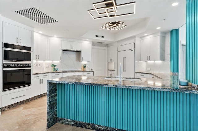 kitchen featuring kitchen peninsula, sink, built in refrigerator, double oven, and white cabinetry