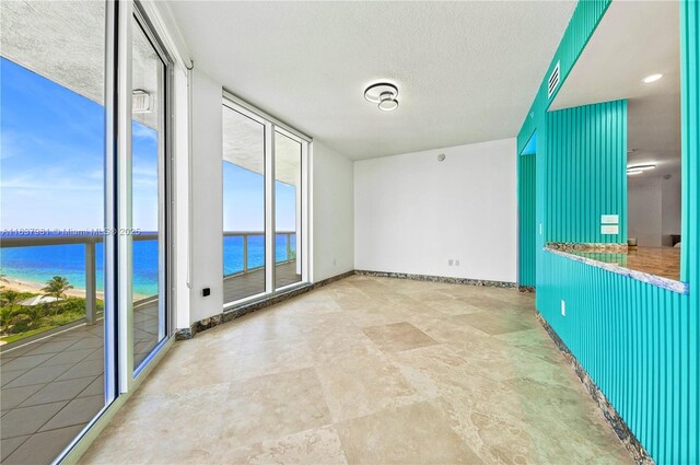 unfurnished living room featuring a textured ceiling, a water view, and a healthy amount of sunlight