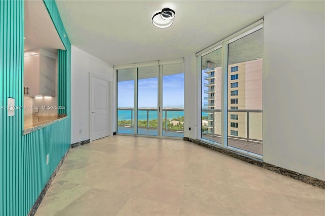 unfurnished room featuring a water view and expansive windows