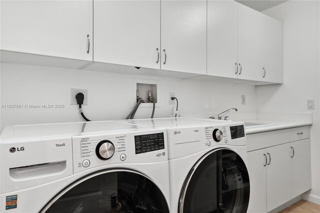 washroom featuring cabinets, sink, and washer and dryer